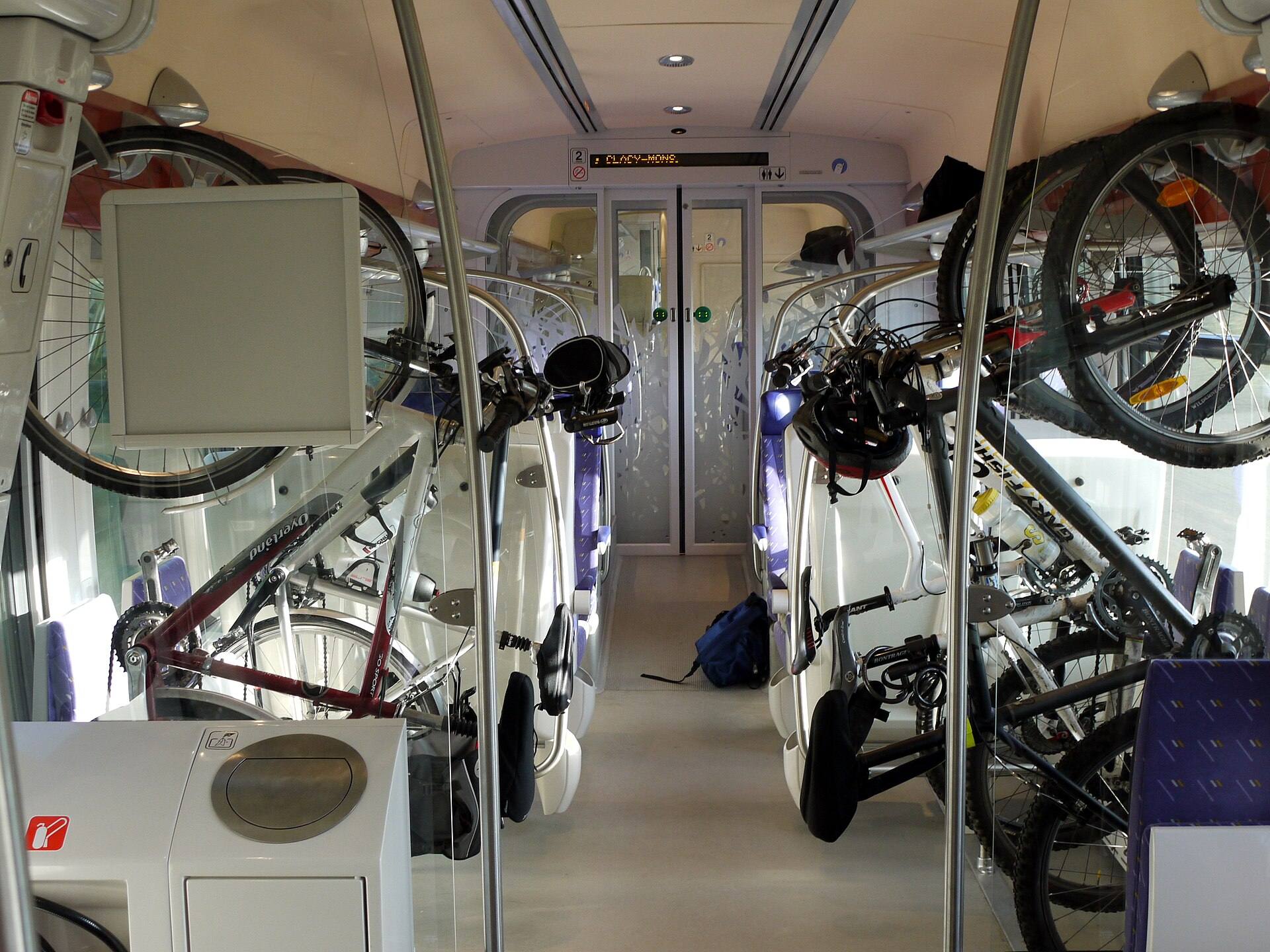 Vélos suspendus par la roue avant aux crochets du compartiment vélo d'un TER
